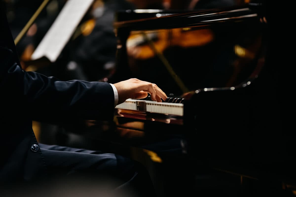 Pianist im Anzug spielt Flügel bei einem Konzert – was kostet Klavierunterricht?